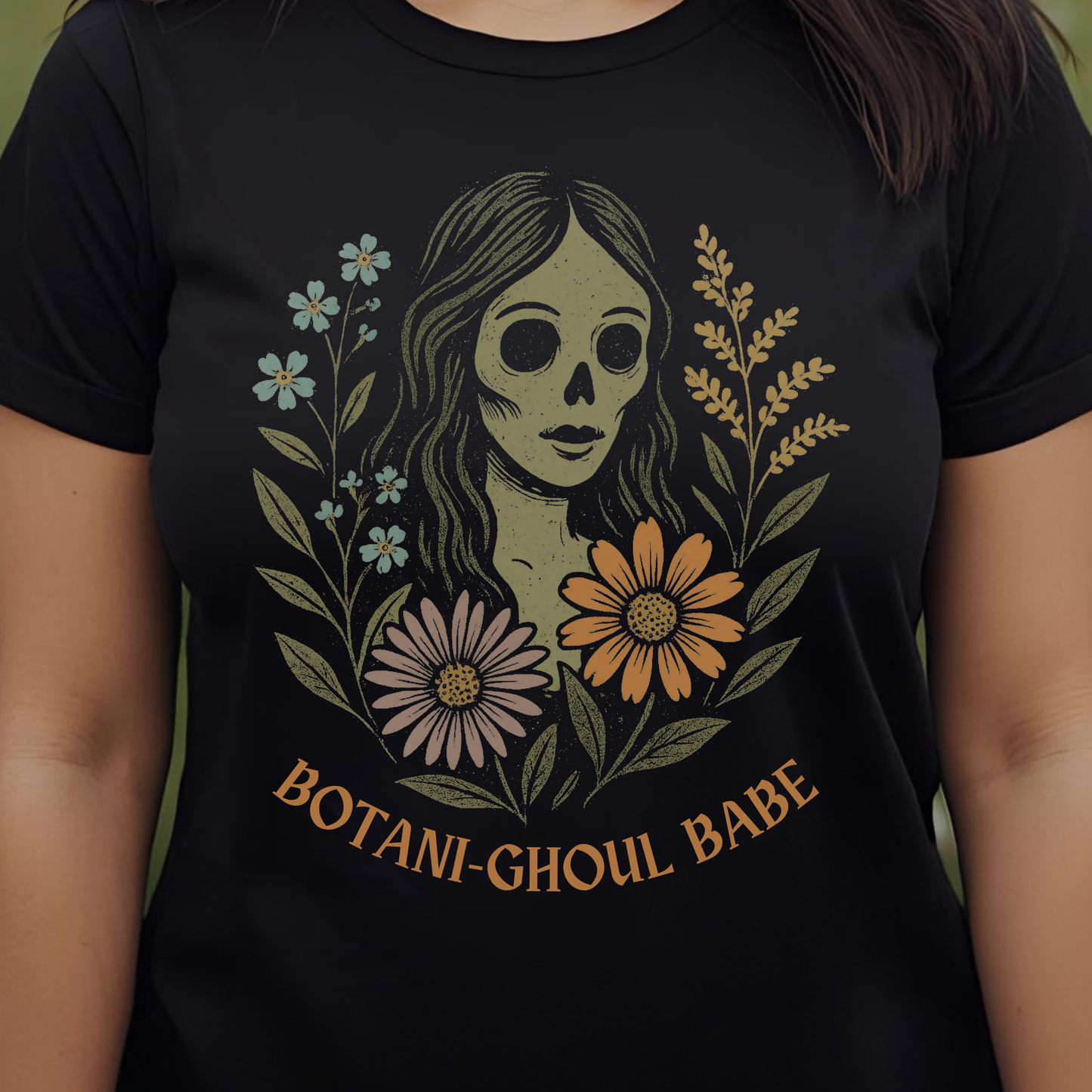 Black t-shirt with a graphic design of a skeleton woman surrounded by flowers and the text 'Botani-Ghoul Babe'.