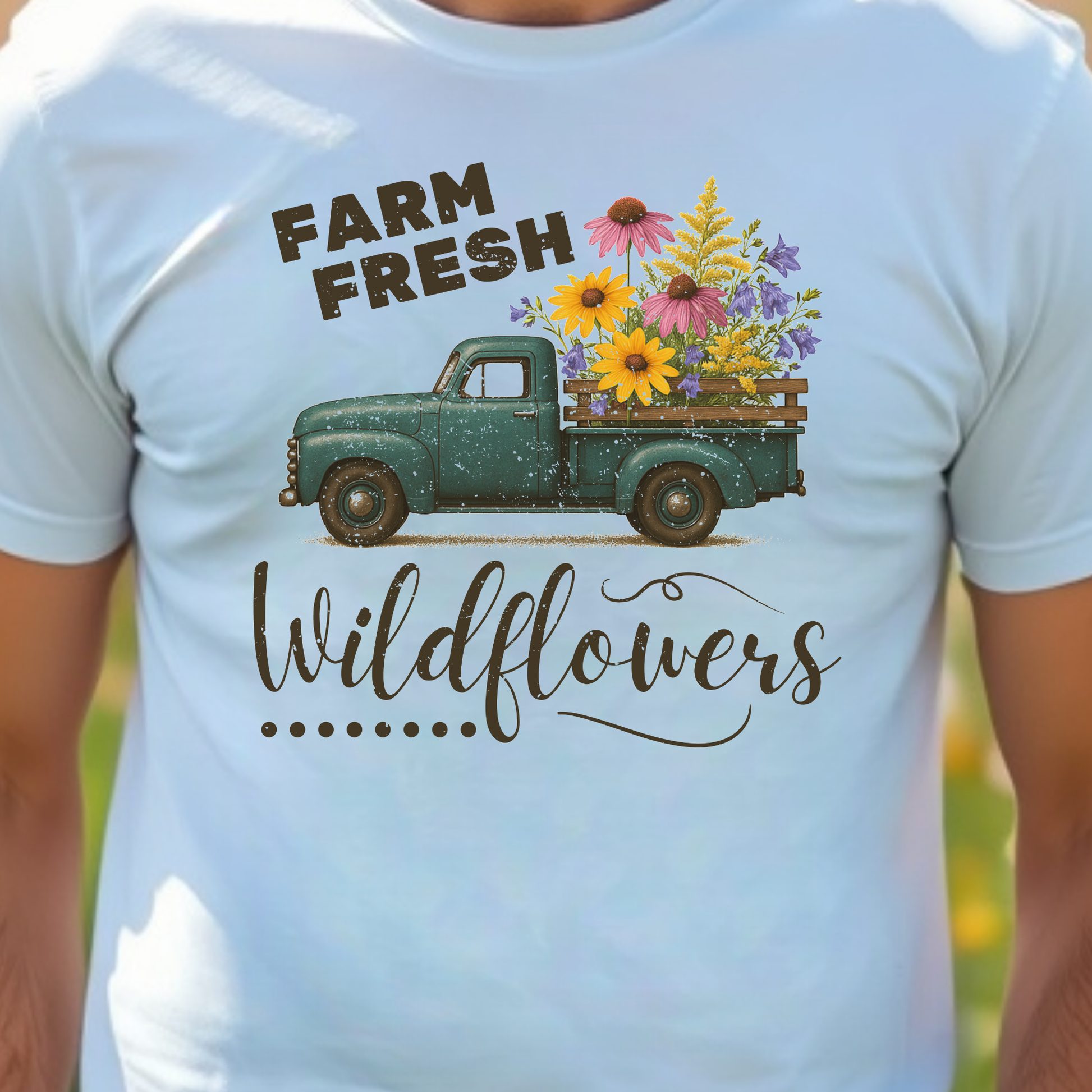 White t-shirt with a graphic of a vintage truck carrying wildflowers and text 'Farm Fresh Wildflowers'.