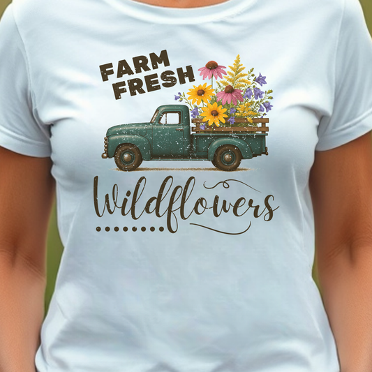White t-shirt with a graphic of a green truck carrying wildflowers and text 'Farm Fresh Wildflowers'.