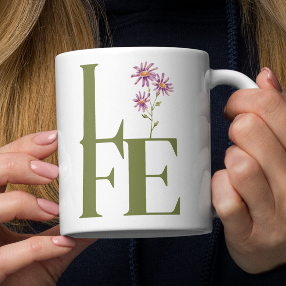 Woman holding a white mug with 'LIFE' and floral design.